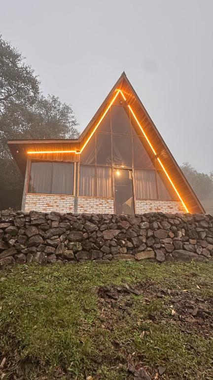 a house with a stone wall and lights on it at Chale Pedra do Sol in Caxias do Sul