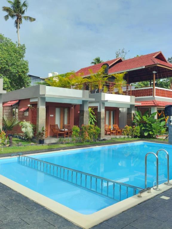 a villa with a swimming pool in front of a house at Aruvi on the cliff in Varkala