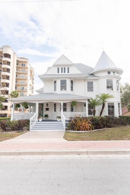 a large white house with a porch and stairs at The Parrish Grove Inn in Cocoa