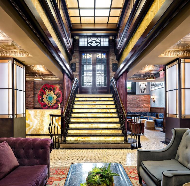 a lobby with a staircase with a couch and a table at Walker Hotel Greenwich Village in New York