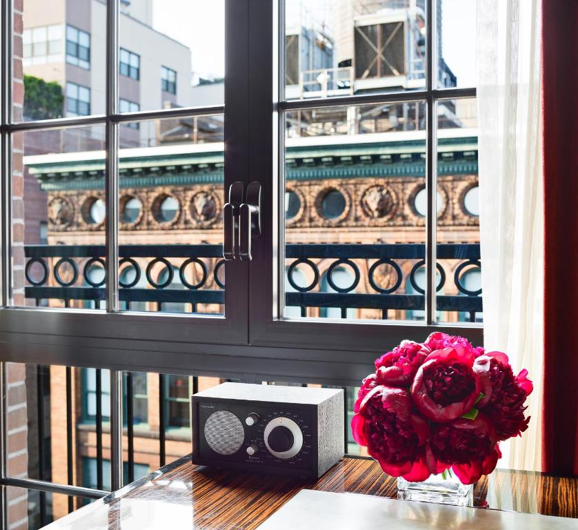 a table with a vase of flowers and a speaker at Walker Hotel Greenwich Village in New York