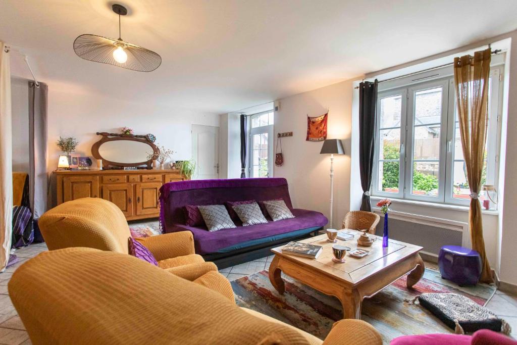 a living room with a purple couch and a table at Maison de La Beslière meublé de tourisme 2 étoiles in Folligny