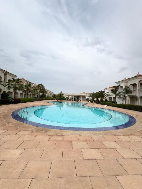 a large blue swimming pool in a courtyard at Cozy Seaside Villa in Bir Jedíd Saint-Hubert