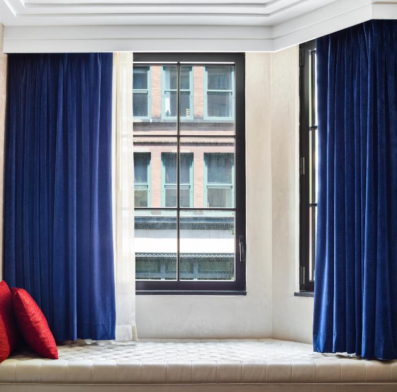 a living room with blue curtains and a window at Walker Hotel Greenwich Village in New York