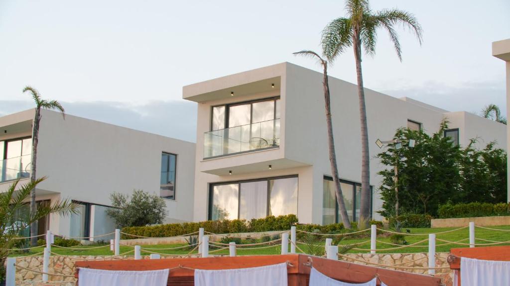a white house with palm trees in front of it at Palmera Dream Vila in Sarandë