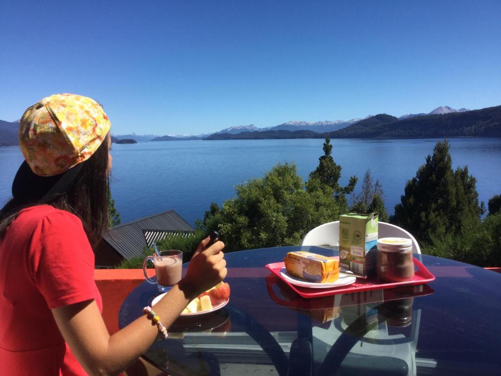 Apartments Seeblick Bariloche في سان كارلوس دي باريلوتشي: امرأة تجلس على طاولة مع صينية من الطعام