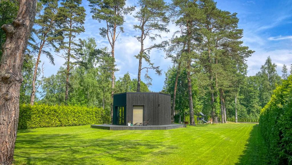 a small black house in a field of grass at Beautiful Tinyhouse near the Beach in Lapmežciems