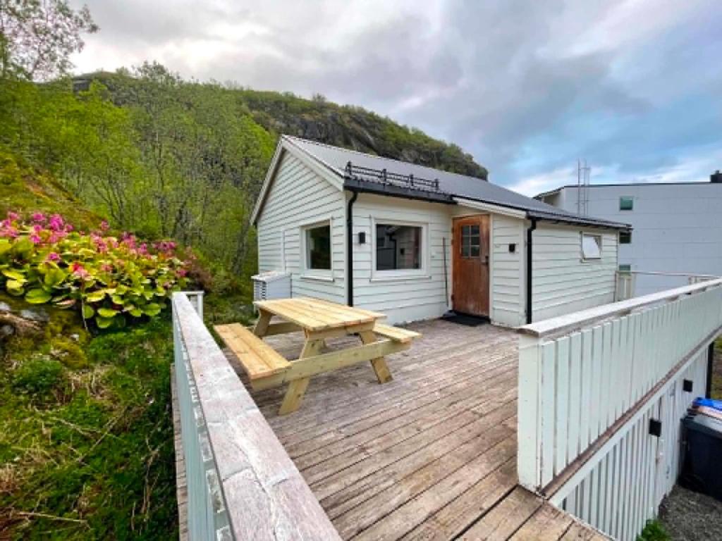 a wooden deck with a picnic table and a building at Svolvær Minihouse in Kongsmarka