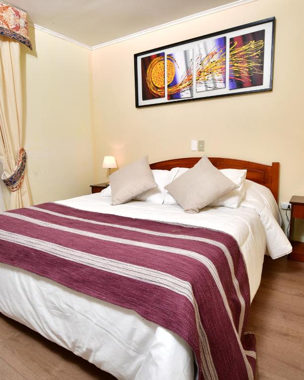 ein Schlafzimmer mit einem großen Bett und einer gestreiften Decke in der Unterkunft Hotel Chalet Suizo in Viña del Mar