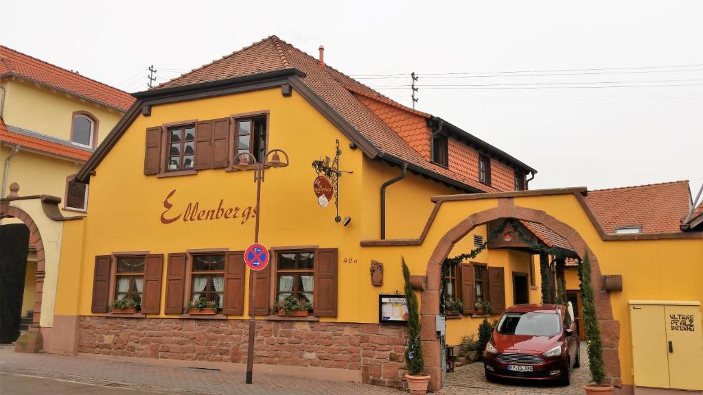 Heßheim的住宿－艾倫伯格餐廳及酒店，一座黄色的建筑,前面有一辆汽车