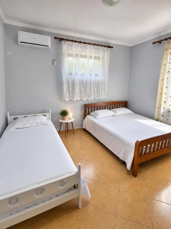 two beds in a bedroom with white walls at Garden Oasis in Vlore in Vlorë