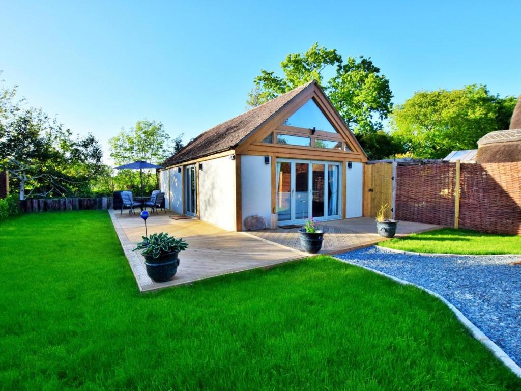 a small cottage with a deck and green grass at 1 Bed in Lymington oc-50723 in Sway