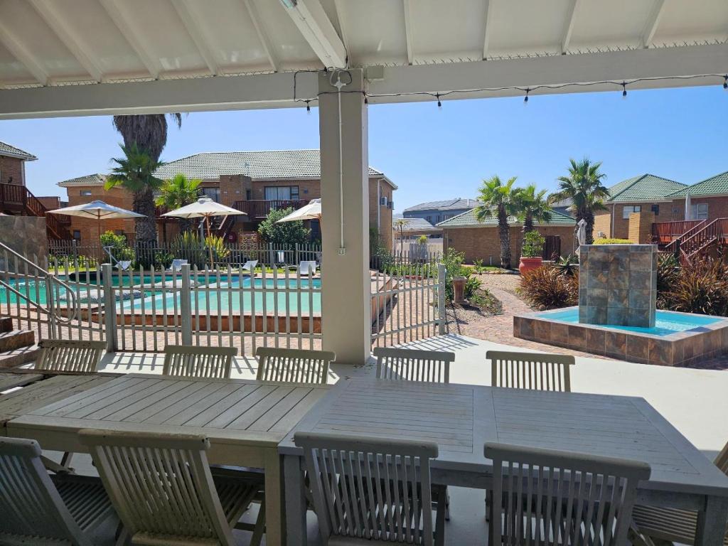 a patio with a table and chairs and a pool at Myoli Beach Breeze in Sedgefield