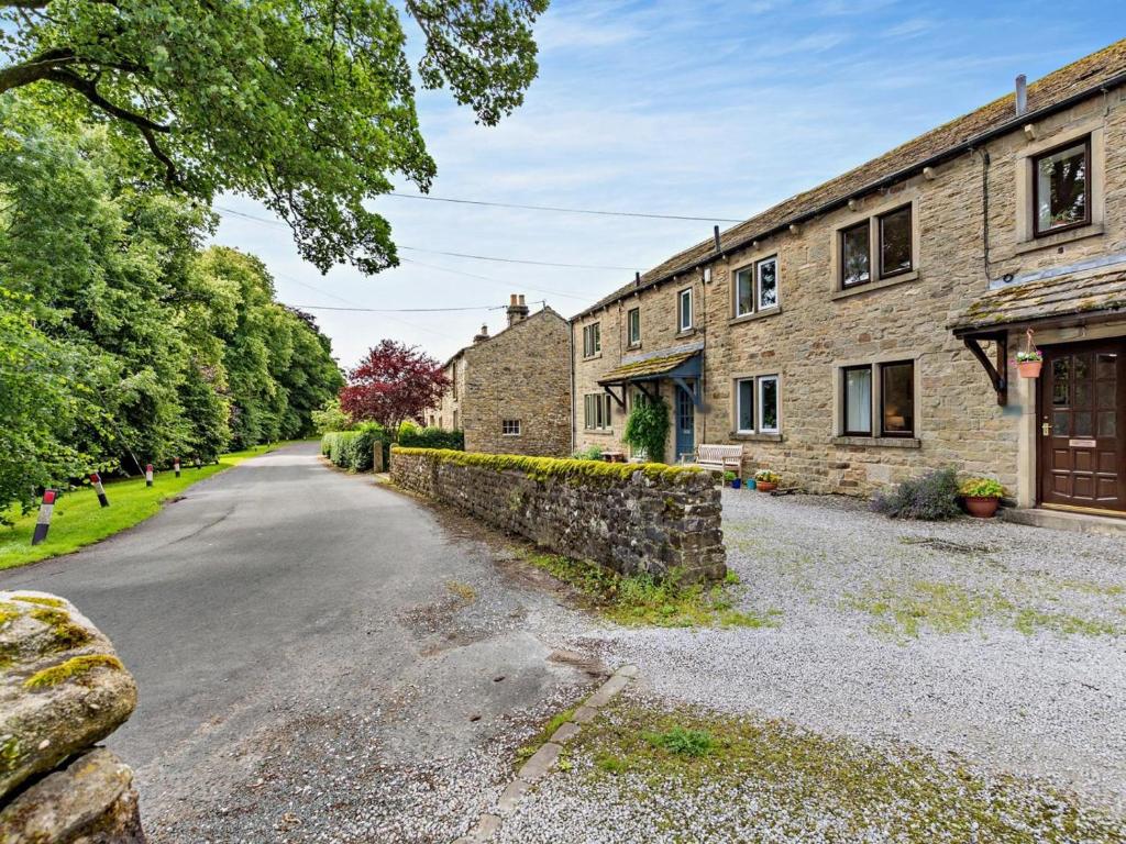 an empty road in front of a stone building at 2 Bed in Skipton oc-92898 in Airton