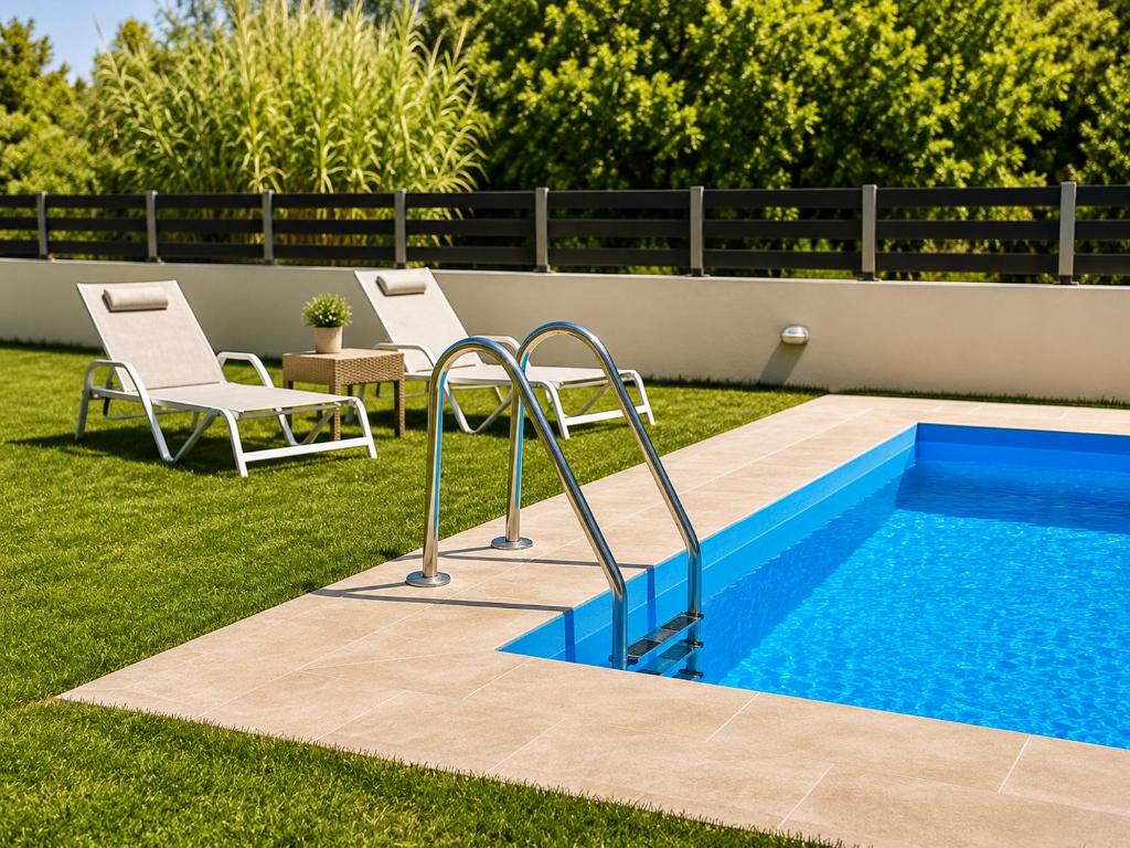a swimming pool with two chairs and a table at Villa Rose Ground Floor - Private Swimming Pool Garden in Koskinou