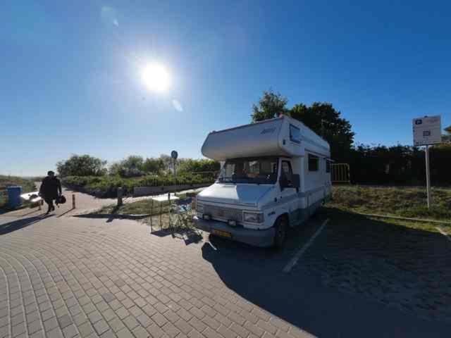 a white camper van parked in a parking lot at Retro Kamper Jastarnia in Jastarnia
