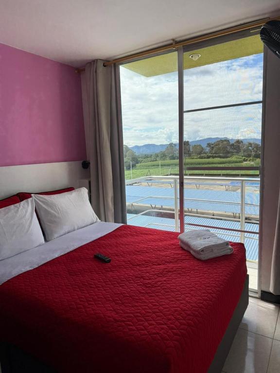 a bedroom with a bed with a red blanket and a window at Apartahotel Paraíso Cafetero Guaduales del café 401B in Montenegro