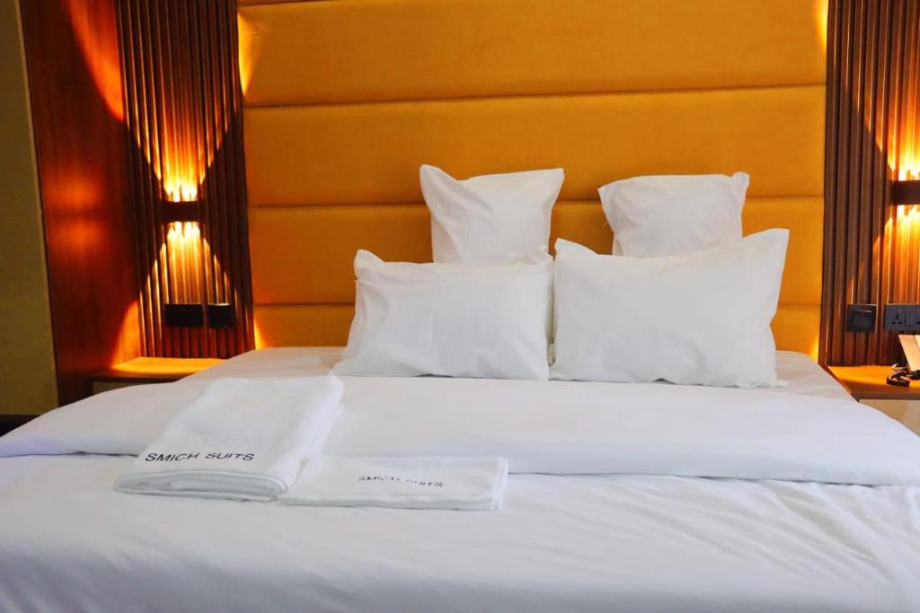 a bed with white sheets and pillows on it at Smich Suites in Abuja