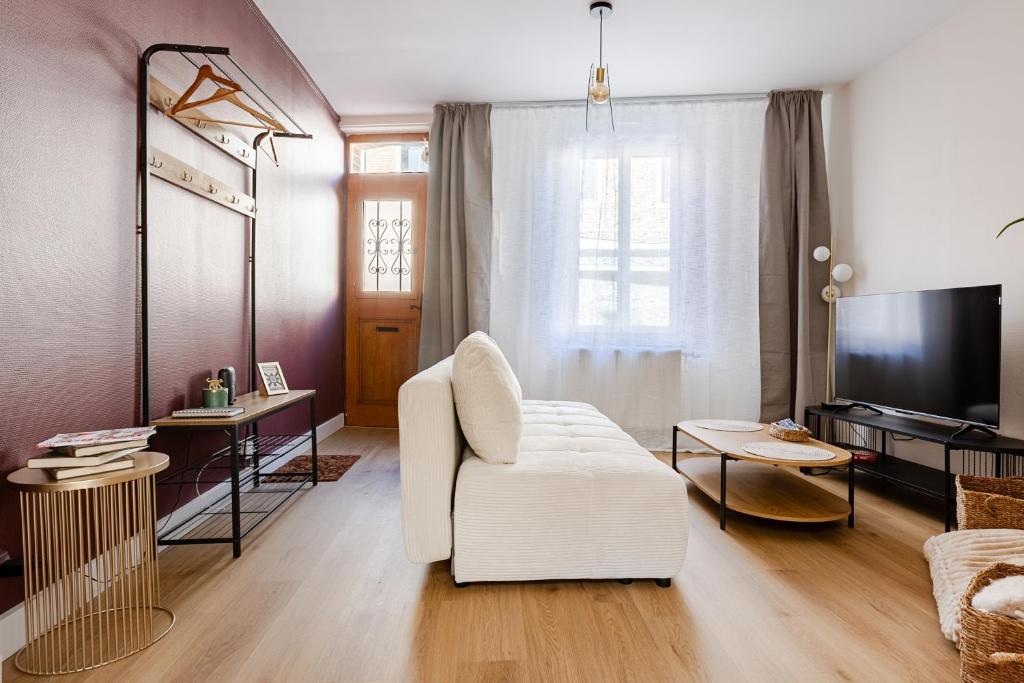 a living room with a white chair and a tv at Le 120 Amiens in Amiens