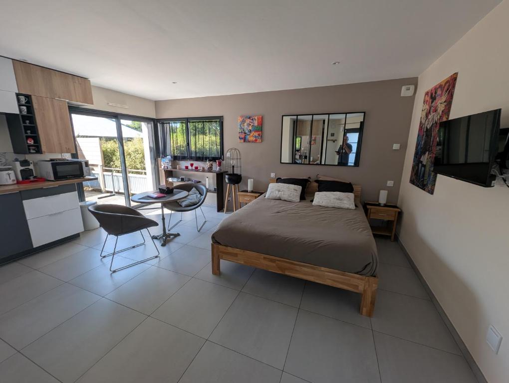 a bedroom with a bed and a table and a kitchen at Studio Castel Binic in Pordic