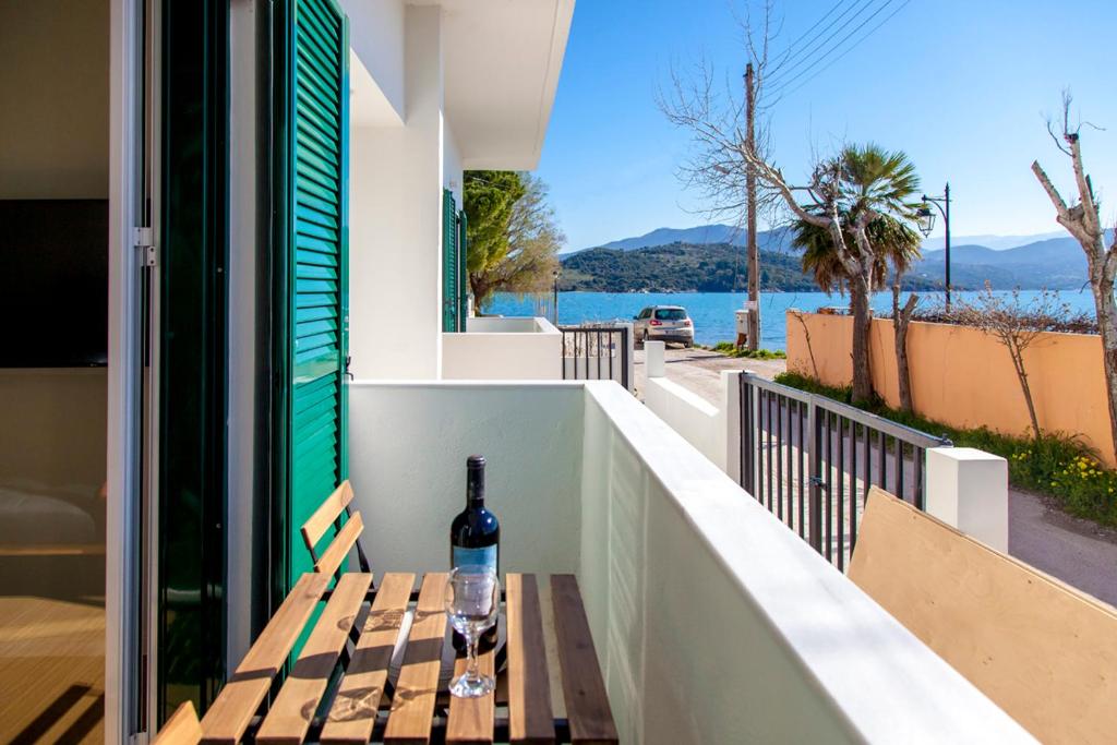a bottle of wine sitting on a wooden bench on a balcony at Coastline Studio Apartment Ligia Bay in Lygia