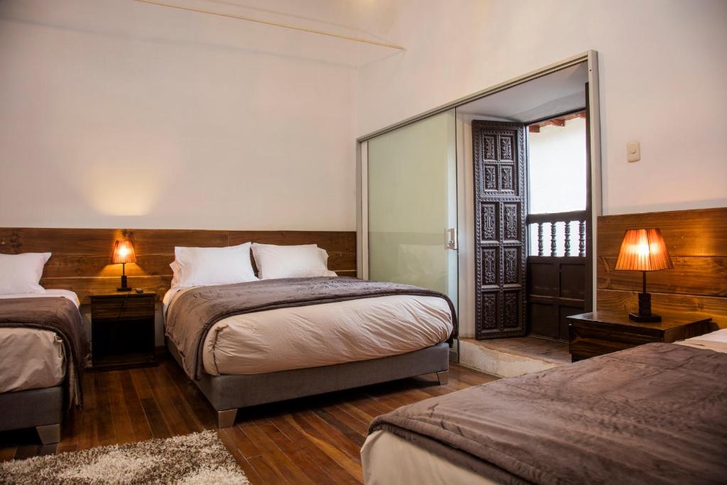 a hotel room with two beds and a mirror at Hotel Casa Fierro Cusco in Cusco
