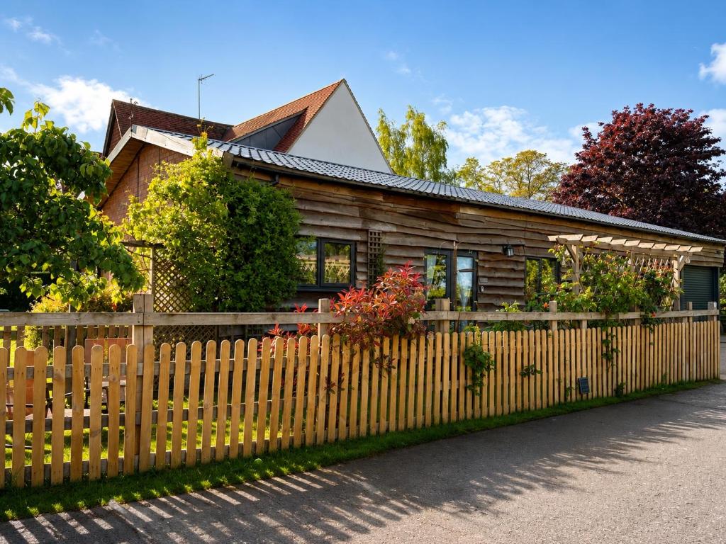 a wooden house with a fence at The Barn at White Rose Cottage in Towcester