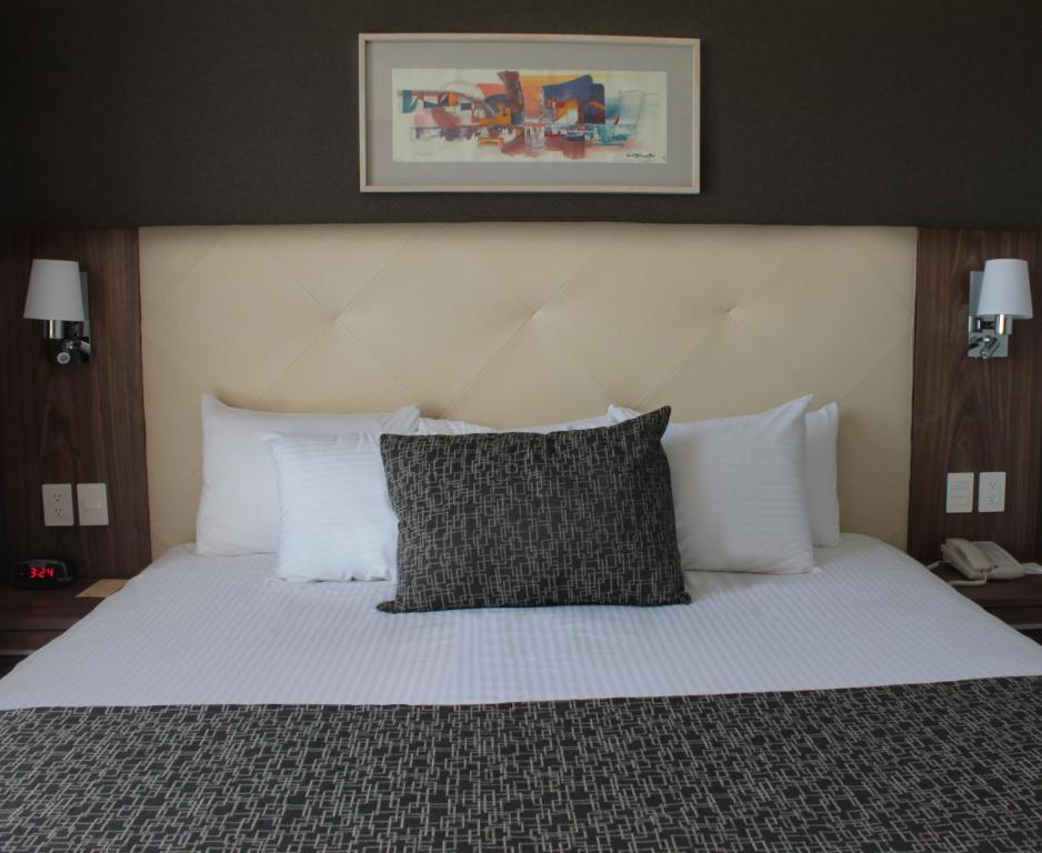 um quarto com uma cama grande e almofadas brancas em Casa Inn Business Irapuato em Irapuato