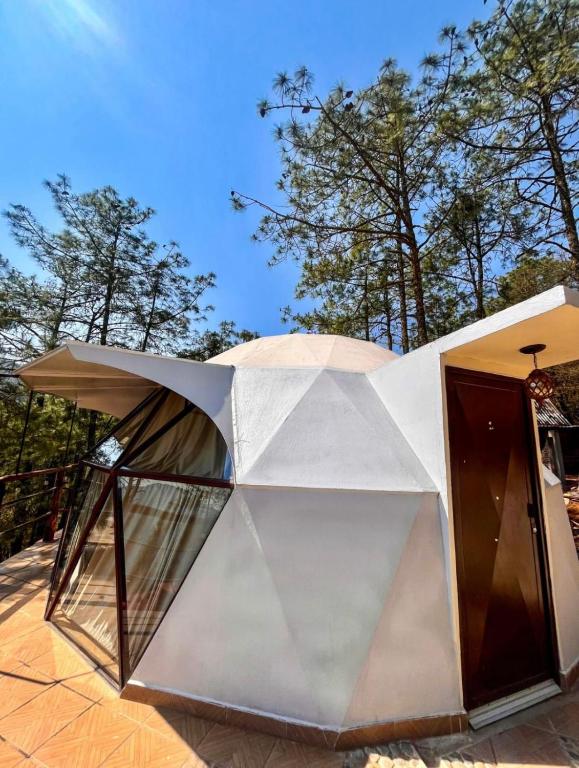 a white house with a glass door on a patio at Glamping Cabañas Luz y Vida in Chignahuapan