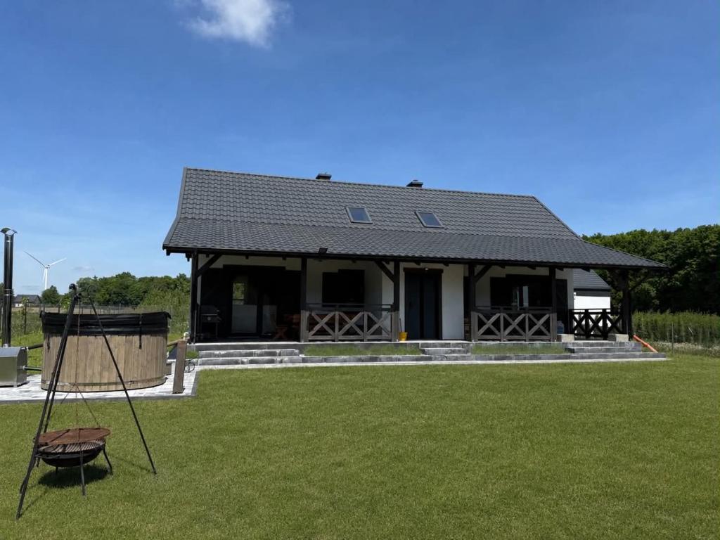 a house with a black roof on top of a yard at Leśna przystań in Trupel