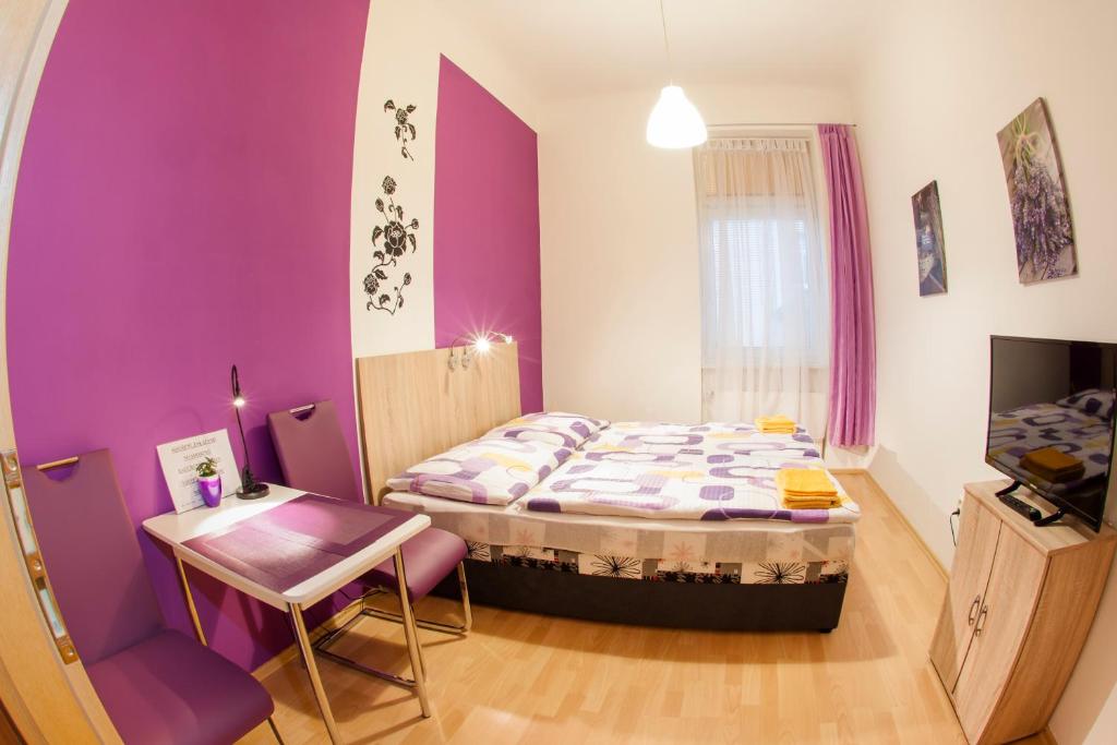 - une chambre avec des murs violets, un lit et une table dans l'établissement Apartmány - Penzion Smetanka, à České Budějovice