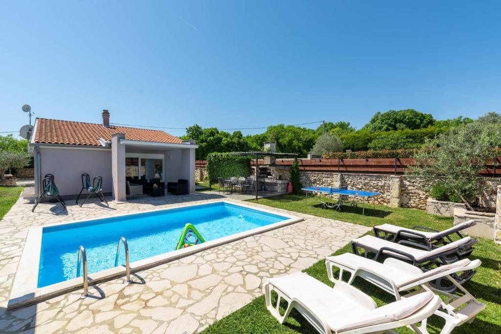 a villa with a swimming pool and lounge chairs at Holiday house Casa Vida in Rakalj