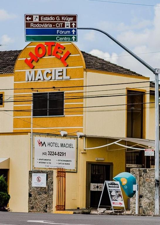 a store with a sign in front of a building at Hotel Maciel in Ponta Grossa