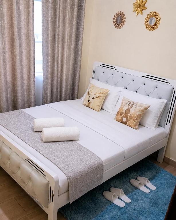a bedroom with a large white bed with slippers on the floor at Cozy cloud in Ruiru