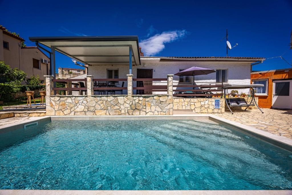 a swimming pool in front of a house at Pool Apartments Franko - Shared Pool in Ližnjan