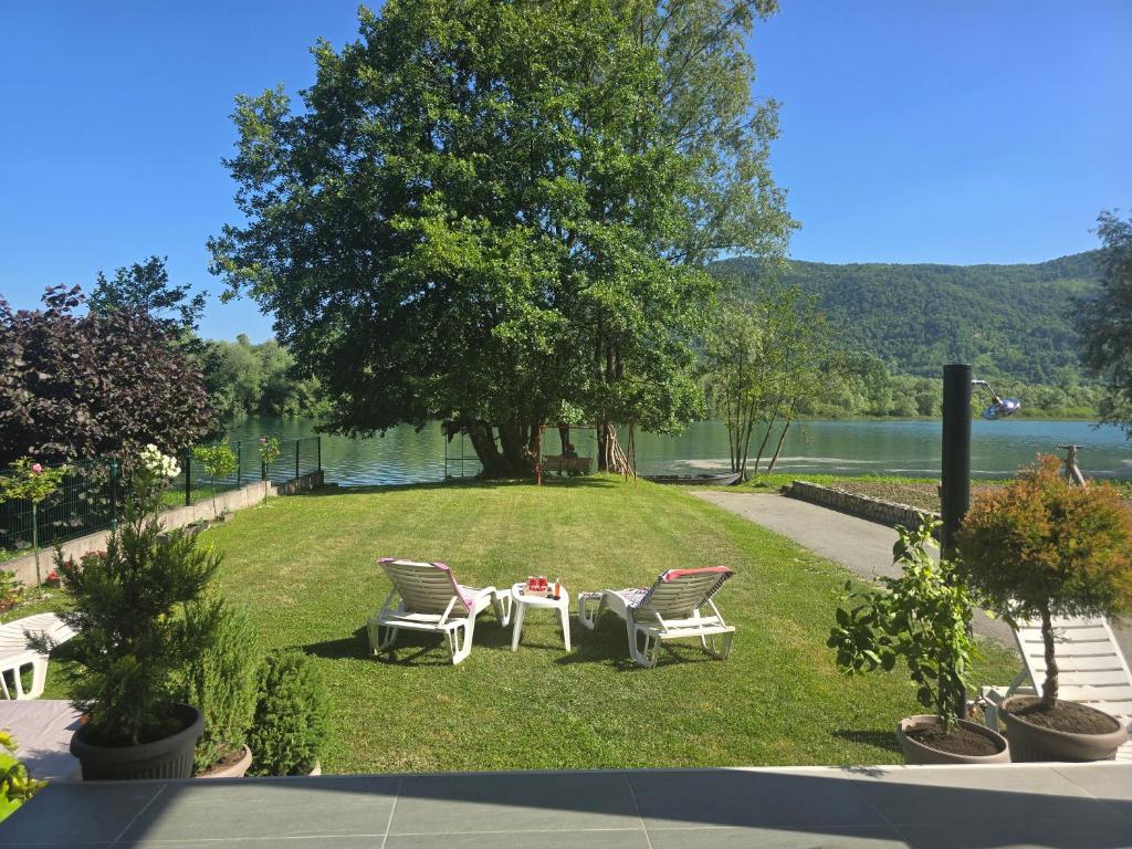 two chairs and a table on a lawn next to a lake at Vikendica Marija, Culine in Mali Zvornik