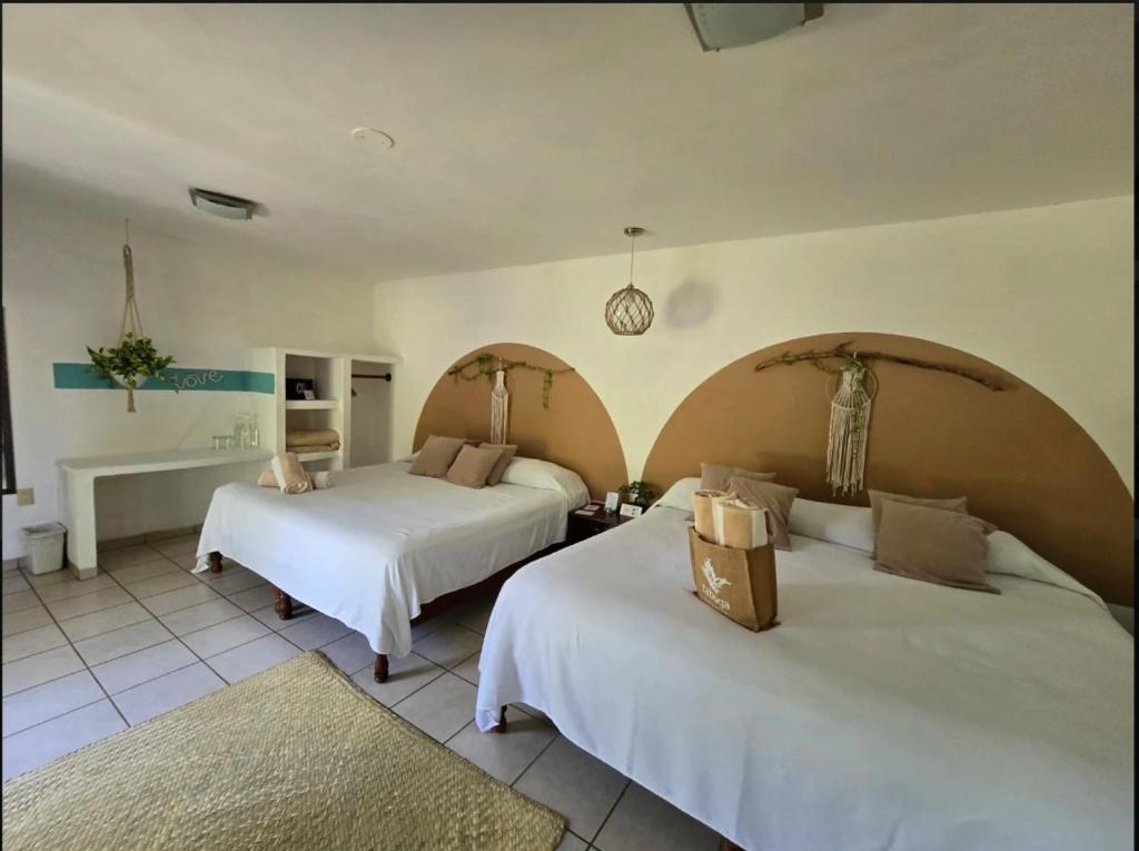 two beds in a room with white walls at Eco Taboutique Hotel & Cabañas in Monte Gordo