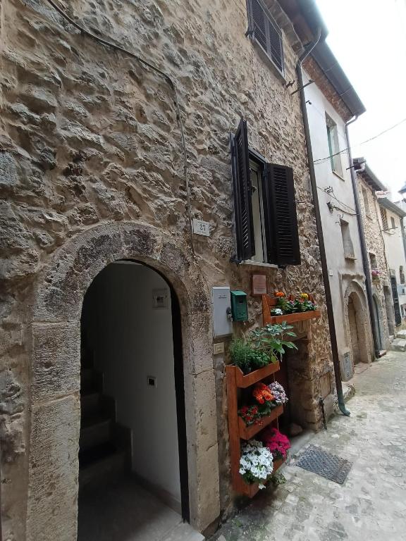 an entrance to a stone building with a door and flowers at Lo chalet del vicolo in Roccasecca dei Volsci
