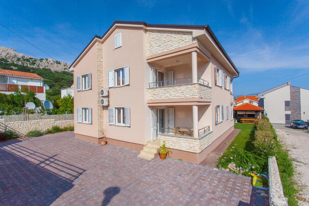 a large pink house on a brick driveway at Apartments Mia in Baška