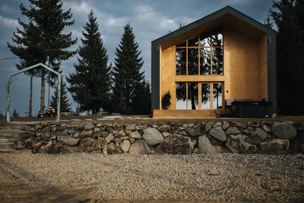 a house with a stone wall in front of it at Lordis Cabin Tihuța in Piatra Fantanele