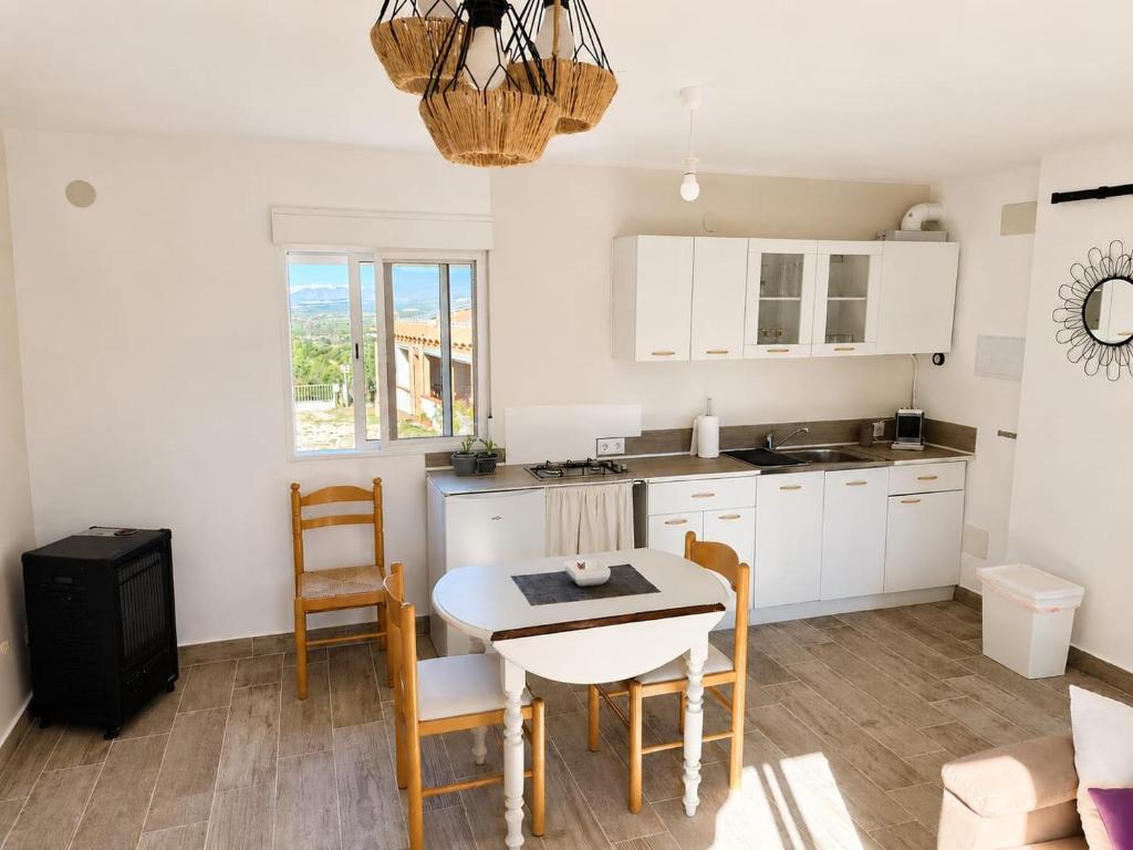 a kitchen with white cabinets and a table and chairs at Maset Paradiso in Vanacloig
