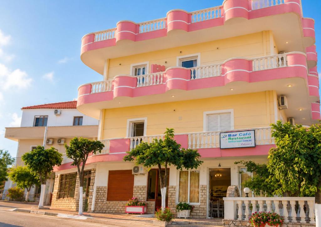 a large yellow building with a pink balcony at Studios Florand Sela Ksamil in Ksamil