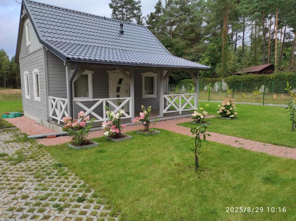 a small gray cottage with a yard with flowers at Chatka Puchatka in Gołubie