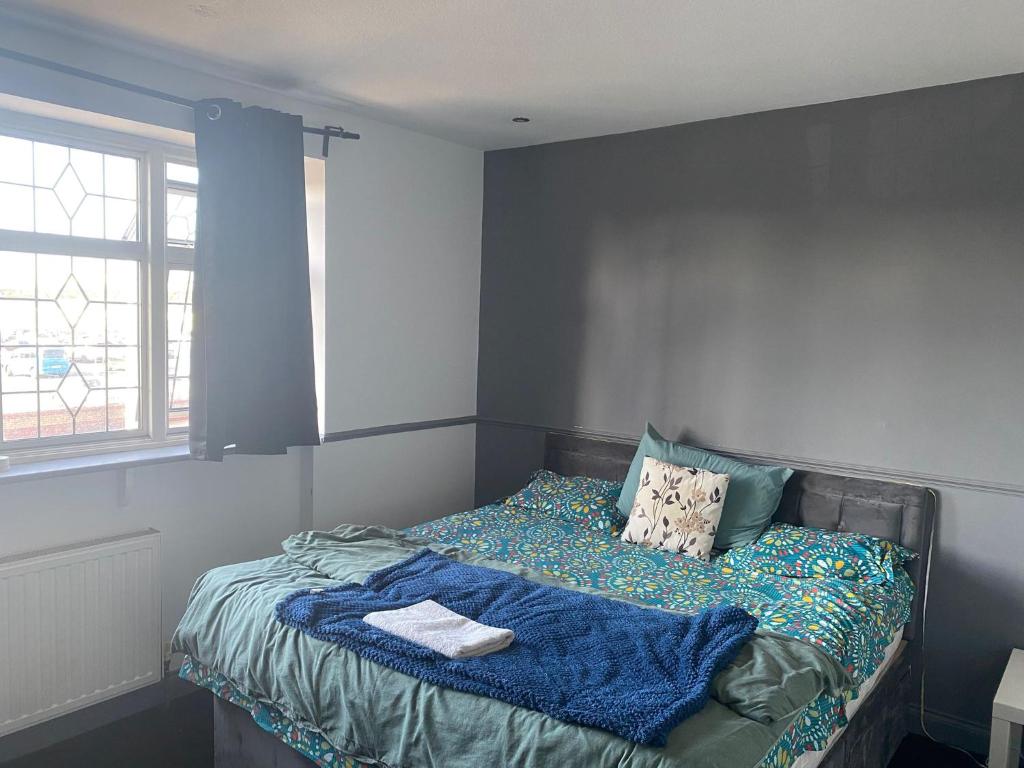 a bedroom with a bed with a blanket and a window at King size room in home for couple or females in Hornchurch
