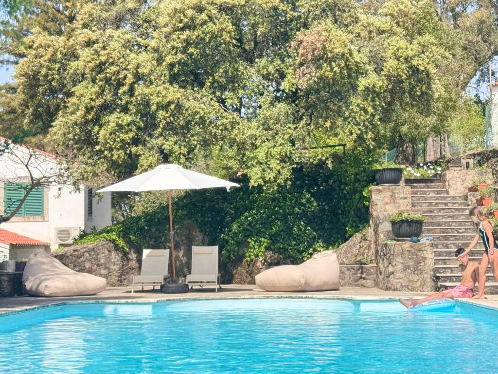 a woman standing next to a swimming pool with an umbrella at Quinta do Carril in Reguengo
