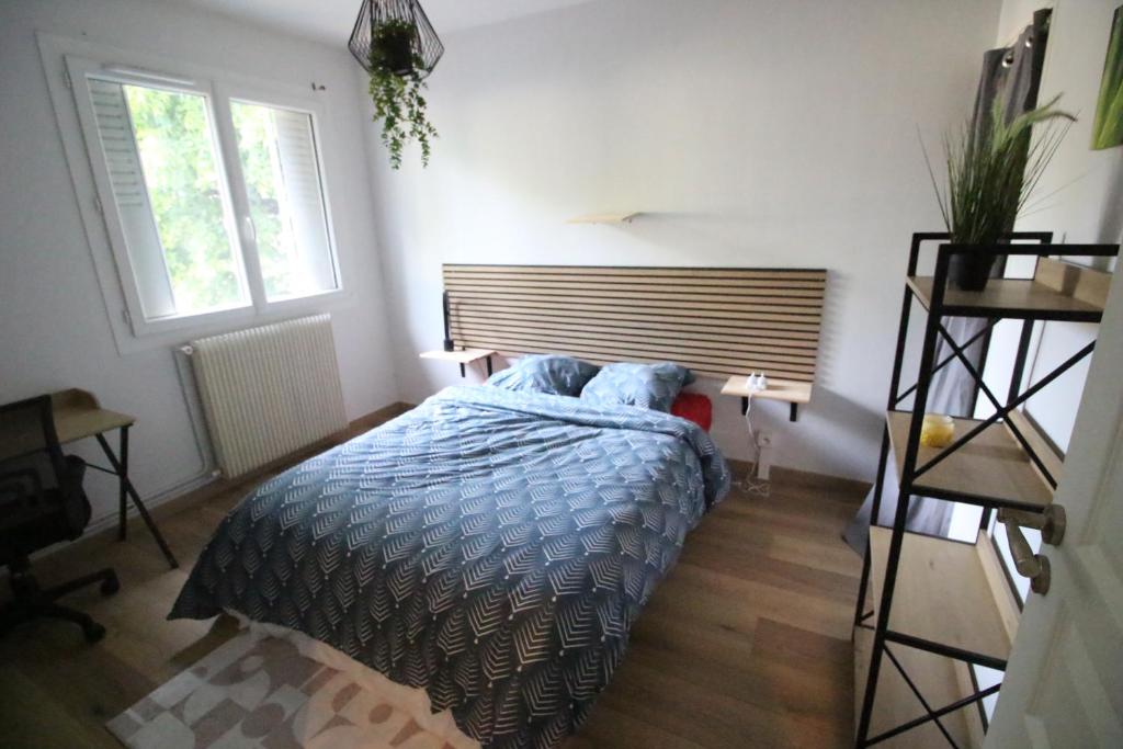 a bedroom with a bed with a blue comforter and two windows at T2 moderne, Parking, Proche Valence & Autoroute in Bourg-lès-Valence