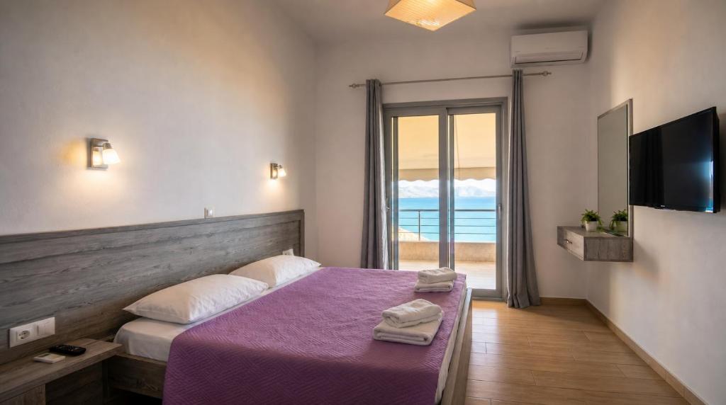 a bedroom with a bed with purple sheets and a television at Blue Sea Apartments in Qeparo