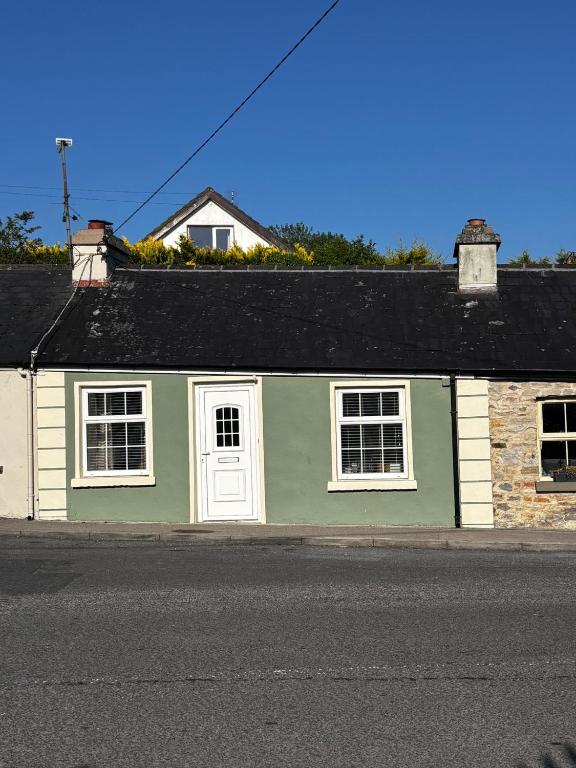 a green and white building on the side of a street at Old Mill Cottage in Swinford