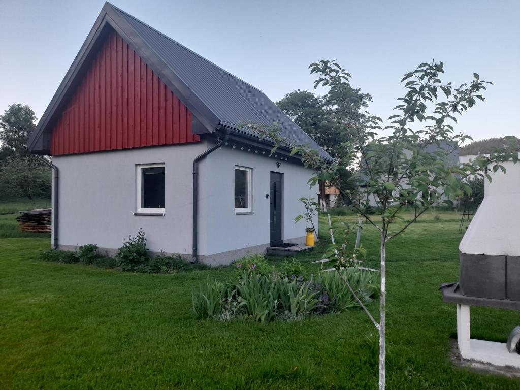 a small white house with a red roof at Domek Pod Górką in Lądek-Zdrój