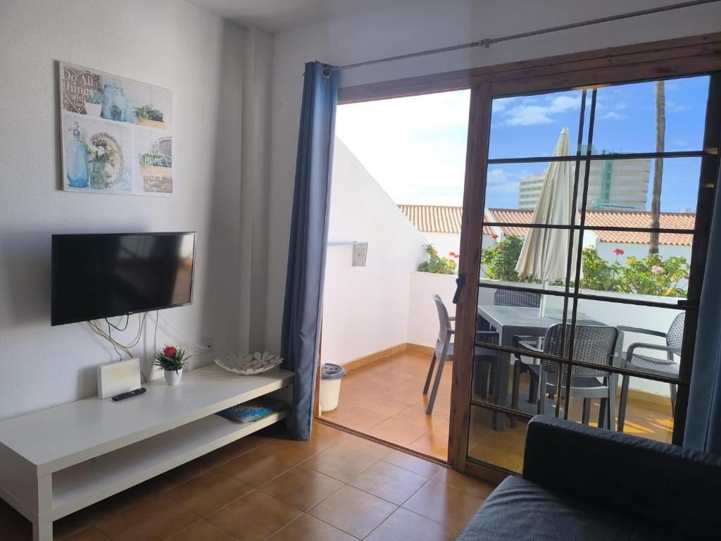 a living room with a television and a table with a view at Garden City apartment Costa Adeje in Costa de Adeje